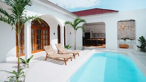 A poolside area with lounge chairs, a pool, and a dining area. - Costa Luna, Modern Mediterranean Villa Near Lancing Beach (Nusa Tenggara Bar.)