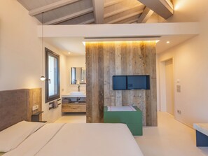 A modern bedroom with a large bed, a built-in vanity, a flat-screen TV, and a wooden accent wall. - San Giuseppe by Interhome (Cecina)