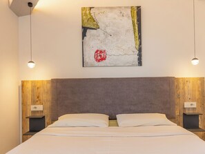 A hotel room with a large bed, wooden headboard, two bedside tables, and a wall-mounted abstract painting. - San Giuseppe by Interhome (Cecina)