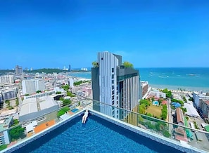 En hög byggnad med en pool på taket som erbjuder utsikt över stadsbilden och havet.