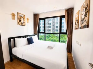 A hotel room with a large bed, a view of greenery through the window, and artwork on the walls. - 2 Bed Room Sea View Unit At Central Pattaya (Muang Pattaya)