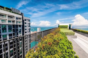 Un bâtiment moderne doté d’un balcon donnant sur une étendue d’eau et un ciel dégagé.