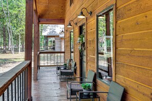 Een houten chalet met een veranda, zitplaatsen buiten en uitzicht op het omliggende bos.