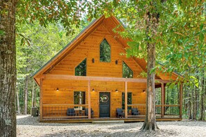 Eine Holzhütte mit Satteldach, großen Fenstern und einer Veranda mit Sitzgelegenheiten.