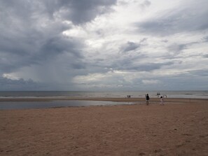 A beach with a wide sandy area and a calm sea under a cloudy sky. - Cozy Home Cha-am Hua Hin 3 mins to beach (Cha-am)