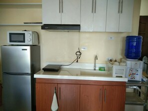 A kitchen with a microwave, refrigerator, sink, and cabinets. - Royal Oceancrest Mactan 1BR (Lapu-Lapu)