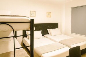 A room with bunk beds, two single beds, a headboard with buttons, and a framed quote on the wall. - Casa Hotel Sweet Home Apt 203 Grupos (Medellín)