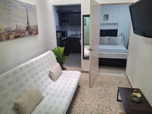 Un espace de vie compact comprenant un canapé, une petite table avec un vase et un lit.
