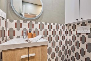 A bathroom with a white sink, a mirror, and a patterned wall. - Superb Apartment 1 Bedroom Center of Paris by Studio Prestige (Paris)
