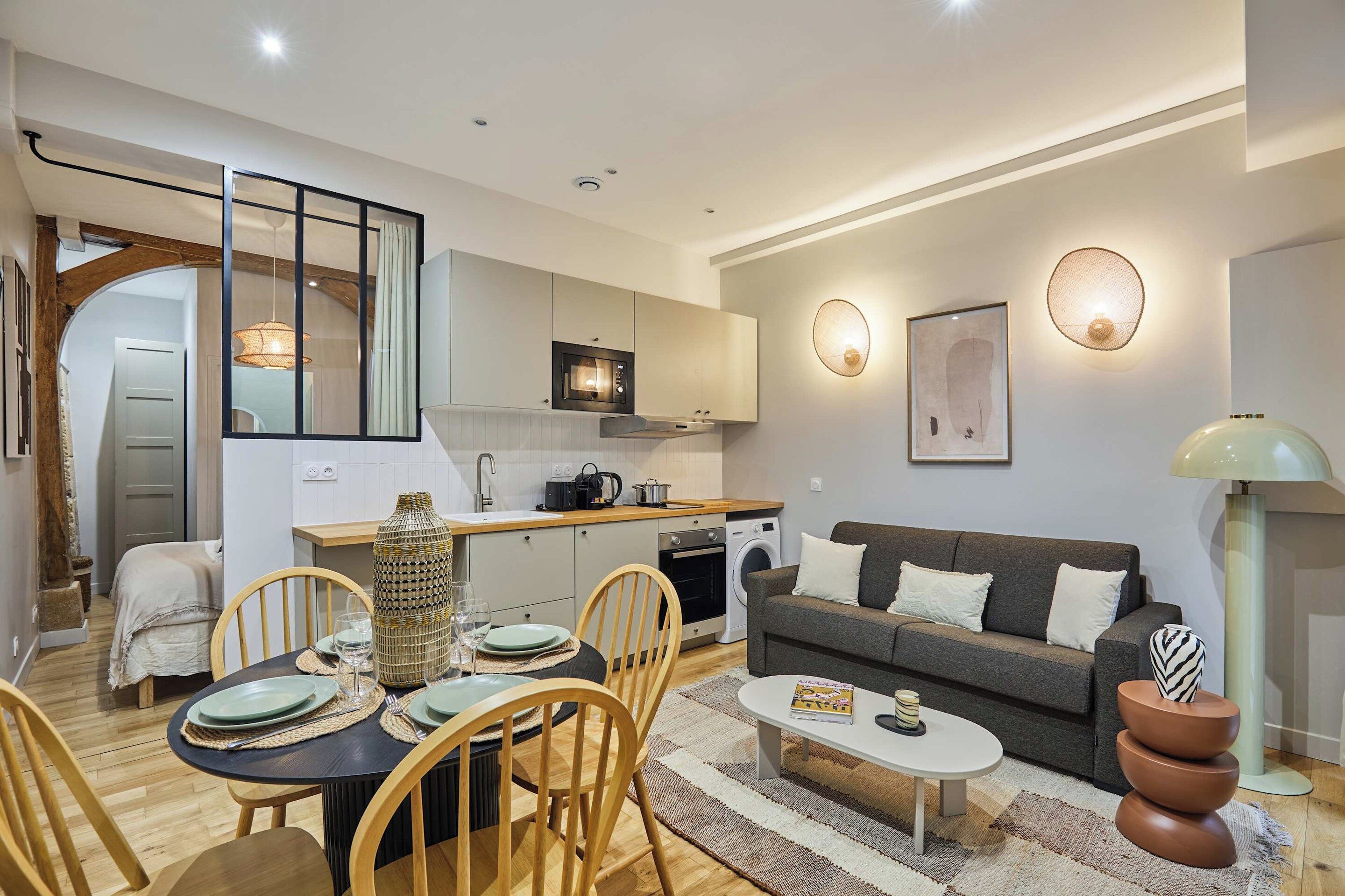 A compact living space with a dining area, kitchenette, and a sofa.