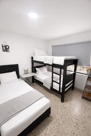 A bedroom with a bunk bed, a single bed, a small table, and a window. - ExclusiveAPT Wifi Balcony Tv Laundry Medellín (Medellín)