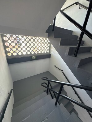 Eine Treppe mit Handlauf und einem Fenster mit geometrischem Muster.