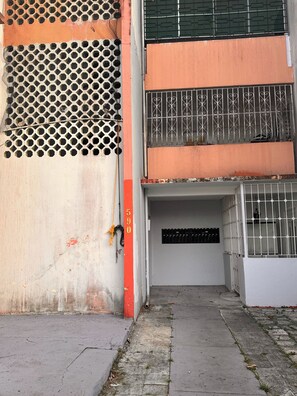 Ein Gebäudeeingang mit einem Metallgitter, einem Betonweg und der Hausnummer 590 an der Wand.
