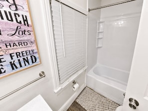 A bathroom with a shower, toilet, and a towel rack.