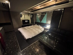 A modern hotel room with a bed, a glass coffee table, a leather sofa, a TV, and a mirror. - HOTEL COCO (Chuo Ward, Sapporo City)