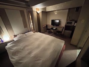 A hotel room with a large bed, a television, a small desk with a chair, and a microwave. - HOTEL COCO (Chuo Ward, Sapporo City)