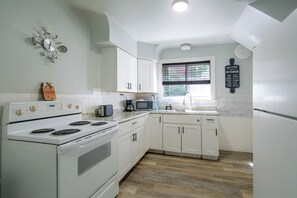 A kitchen with white cabinets, a stove, a microwave, and a window with blinds. - Family Apt 7 Mi to Gateway Arch, Museums & More! (St. Louis)