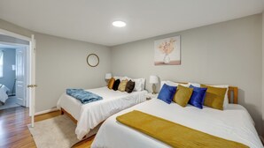 Habitación de hotel con dos camas, una puerta que da a un baño y un cuadro en la pared.