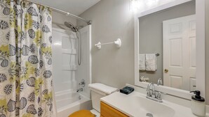 Un baño con ducha, inodoro, lavamanos y espejo.