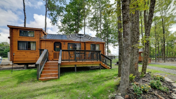 Eine Holzhütte mit einer Terrasse, Treppe und einer kleinen Veranda.