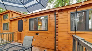 Eine Holzhütte mit einer Terrasse, einem Tisch mit Stühlen und einem Fenster mit Vorhängen.