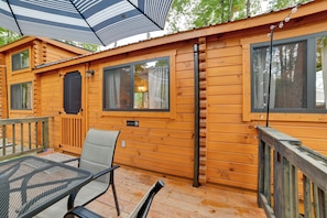 A wooden cabin with a deck, a table with chairs, and a window with curtains. - Hiking/Biking Trails On-Site! Rustic Oxford Cabin (Oxford)