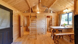 Ein Holzblockhaus-Innenraum mit Essbereich, Küche und Bad.