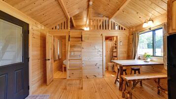 L’intérieur d’une cabane en bois comprend un coin repas, une cuisine et une salle de bain.