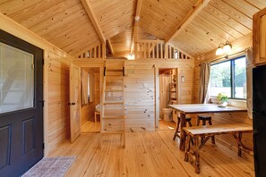 A wooden cabin interior with a dining area, a kitchen, and a bathroom. - Hiking/Biking Trails On-Site! Rustic Oxford Cabin (Oxford)