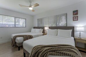 Ein Hotelzimmer mit zwei Betten, einem Deckenventilator und großen Fenstern mit Jalousien.