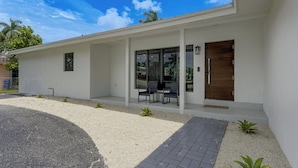 A modern house with a covered porch, a wooden door, and a gravel driveway. - Waterfront Hollywood Oasis w/ Private Pool! (Hollywood)