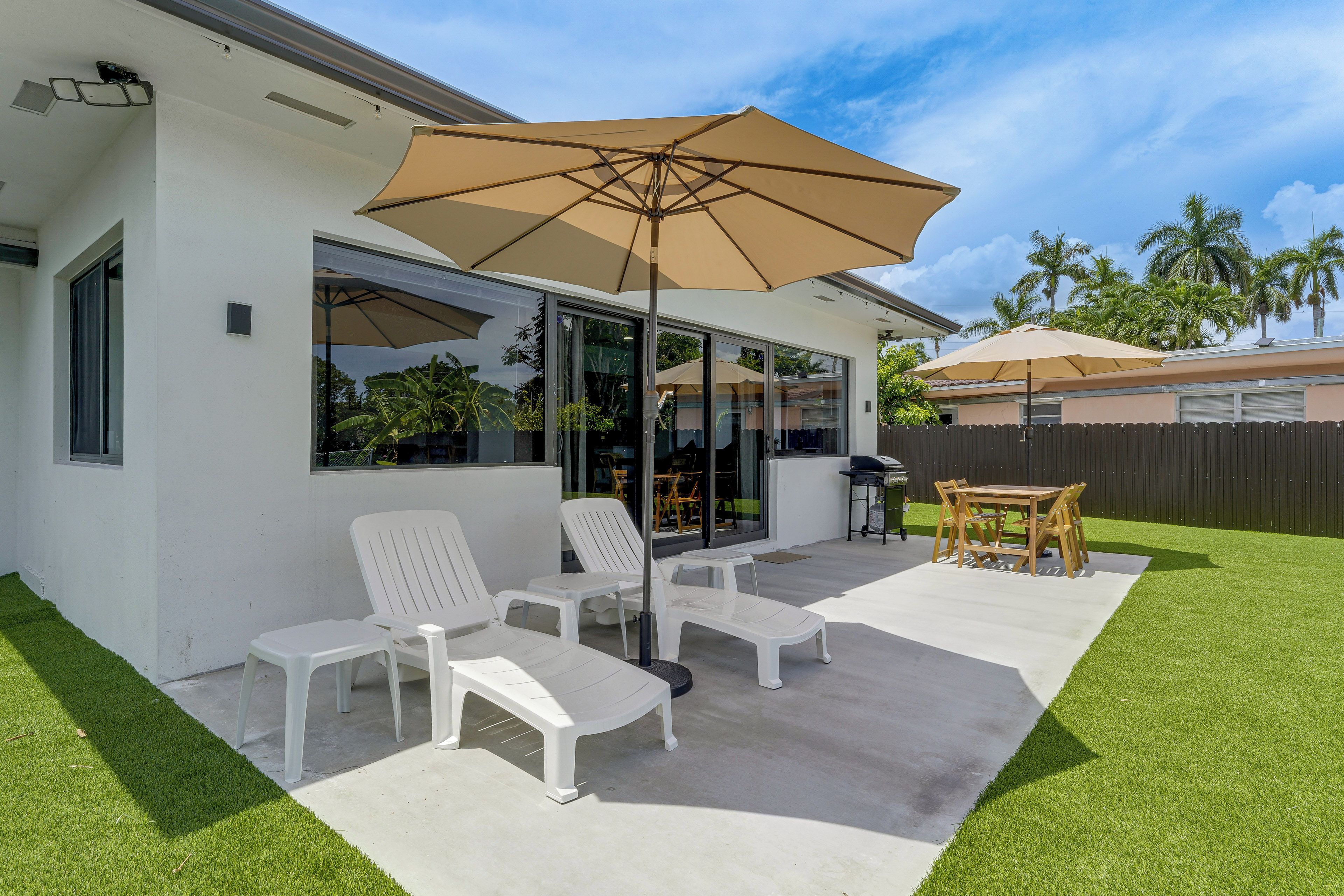 A patio area with a table and chairs, a large umbrella, and a glass door leading to an interior space.