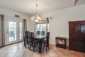 A dining area with a table and chairs, a chandelier, a cabinet, and a door leading to an outdoor area. - Arizona City Monthly Rental w/ Yard & Workspaces (Arizona City)