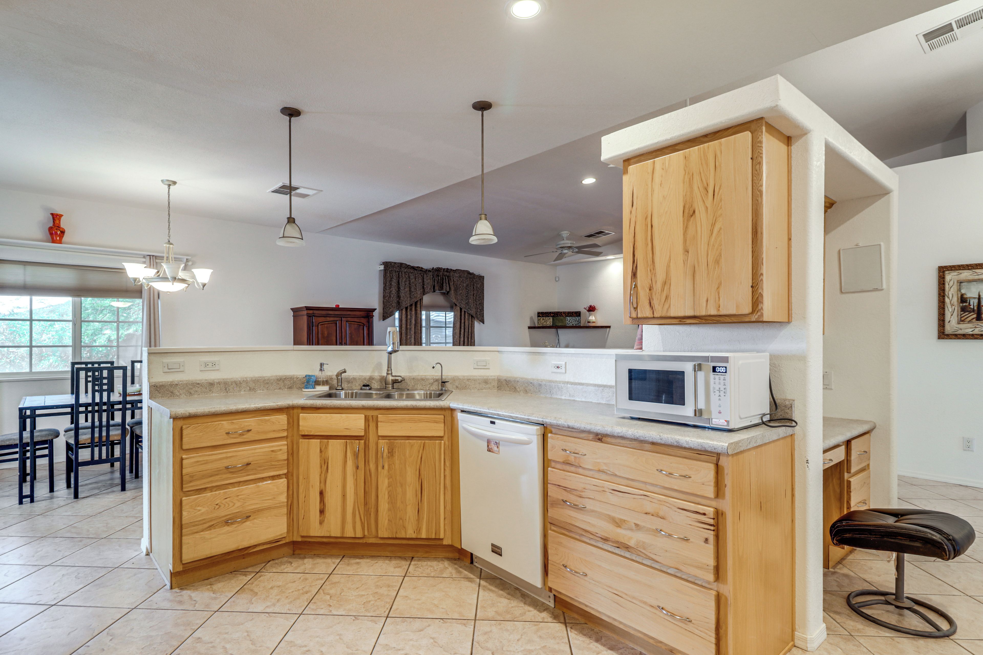 A kitchen with wooden cabinets, a built-in microwave, and a dining area with chairs.
