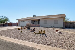 A single-story house with a garage, surrounded by a gravel driveway and various cacti. - Arizona City Monthly Rental w/ Yard & Workspaces (Arizona City)