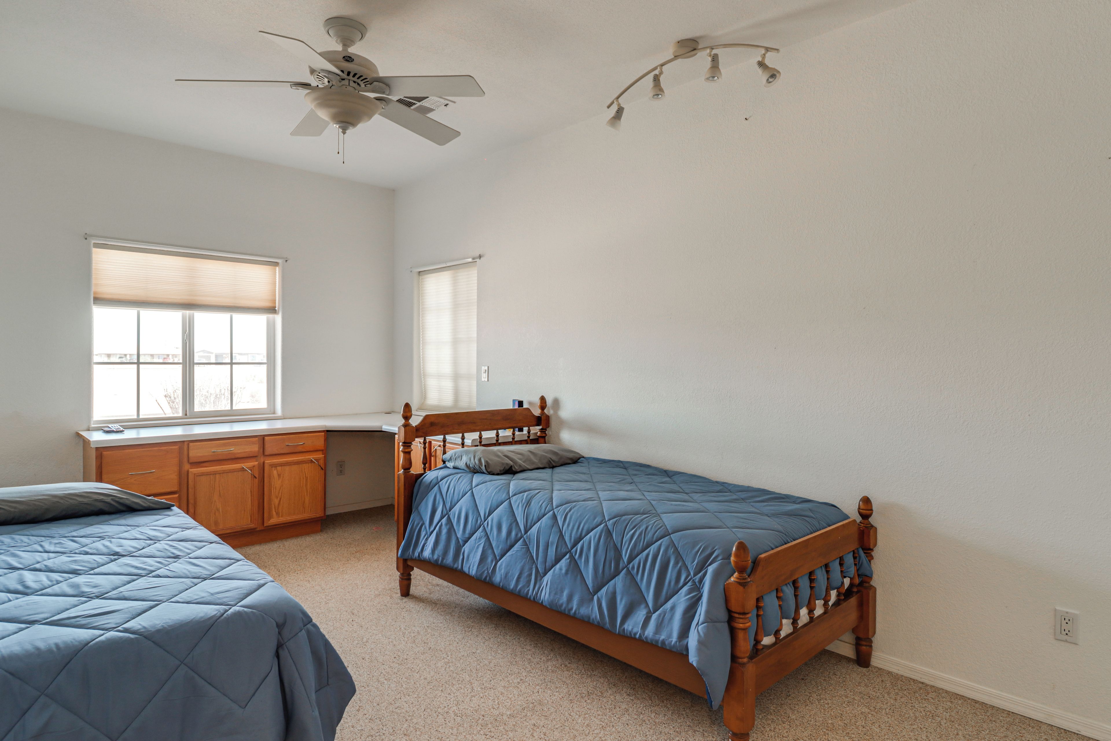 A bedroom with two beds, a ceiling fan, and a window with blinds.