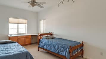 A bedroom with two beds, a ceiling fan, and a window with blinds.