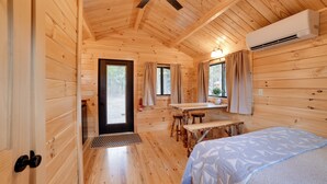 Ein Holzblockhaus-Innenraum mit einem Bett, einem Esstisch und einem Deckenventilator.