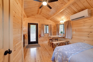 A wooden cabin interior with a bed, a dining table, and a ceiling fan. - Cozy Couple’s Cabin w/ Trail Access in Oxford (Oxford)