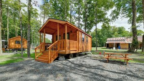 Eine Holzhütte mit Veranda und Treppe, umgeben von Bäumen.
