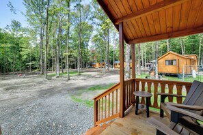 A wooden deck with a view of a forest and cabins.