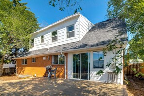 Ein zweistöckiges Haus mit überdachter Terrasse, Backsteinelementen und einer Holzterrasse.