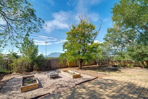 A backyard with raised garden beds, a wooden deck, and a wooden fence. - Mountain-View Basecamp in Central Colorado Springs (Colorado Springs)