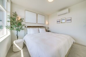 A bedroom with a bed, a nightstand, a lamp, a potted plant, and wall art. - Rooftop Fire Pit & Mtn Views! Seattle Townhome (Seattle)