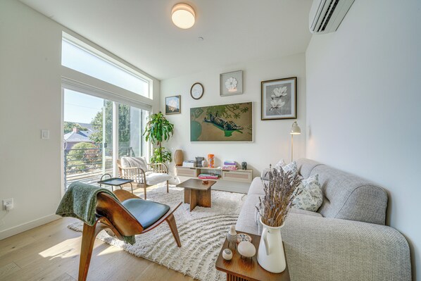 Un salon moderne avec un canapé, une table basse, un fauteuil et une grande fenêtre.