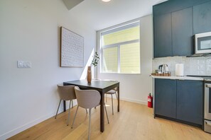 Une cuisine moderne avec des meubles de couleur sombre, un four à micro-ondes et un coin repas comprenant une table et des chaises.