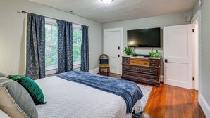 A bedroom with a bed, a dresser, a television, and a window with curtains. - Downtown Salem Home: Walk to Main Street! (Salem)