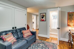 A living room with a black leather sofa, a colorful throw blanket, and a patterned rug. - Downtown Salem Home: Walk to Main Street! (Salem)