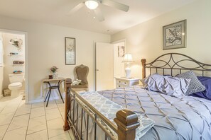 Ein Schlafzimmer mit einem Bett, einem Schreibtisch, einem Stuhl, einem Nachttisch und einem Deckenventilator.