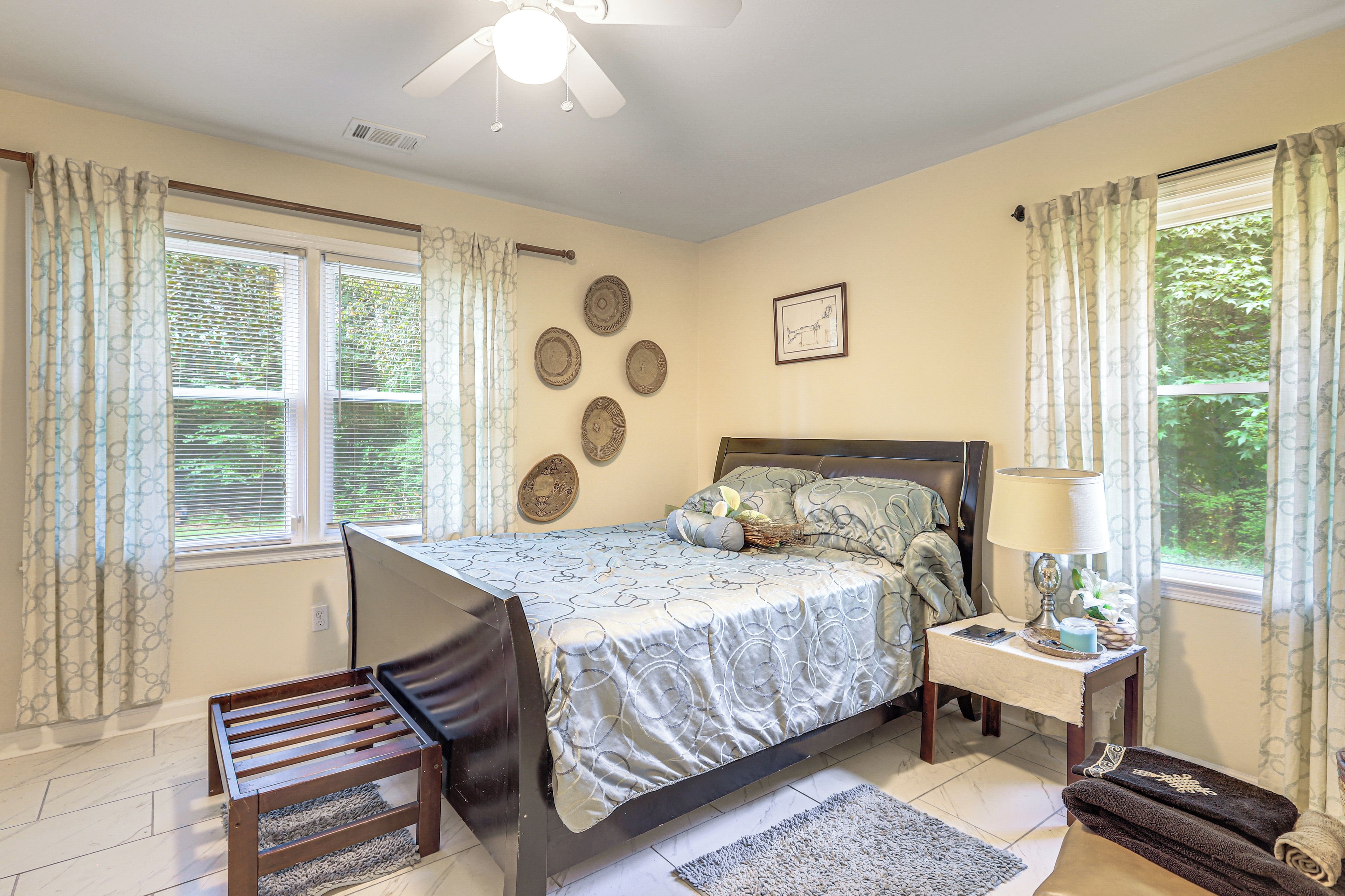 A bedroom with a bed, bedside table, lamp, and a chair.